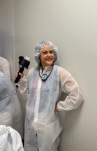 Smiling woman in protective gown holding camera